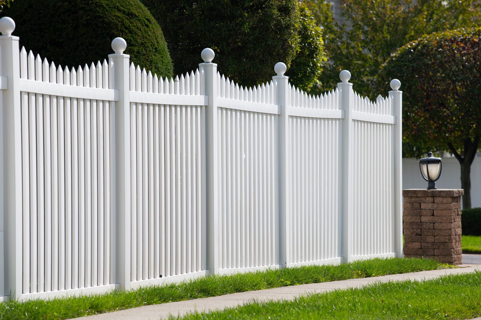 Tall scalloped white vinyl picket fence