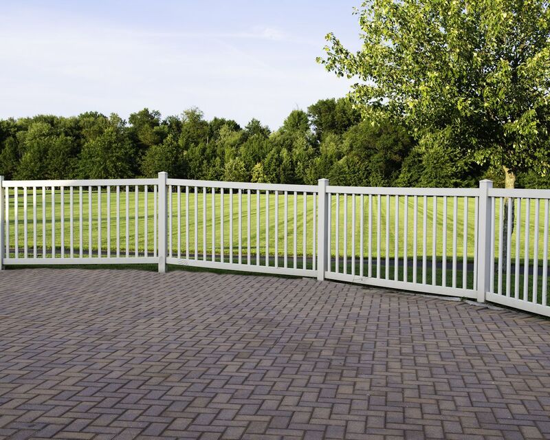 White vinyl closed picket fence bordering a paver patio