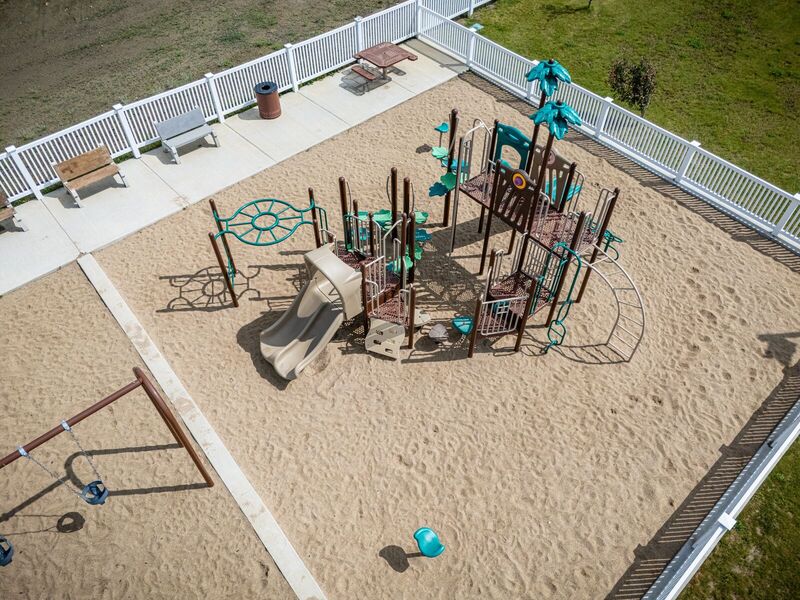 Aerial view of a white vinyl closed picket fence enclosing a playground