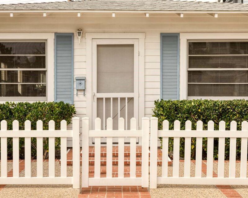 White vinyl three-foot picket fence and gate at a cottage entry