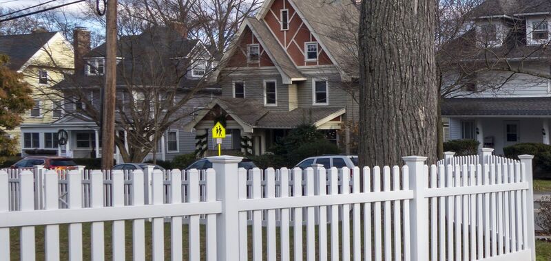 White vinyl straight picket fence with flat post caps along a residential street