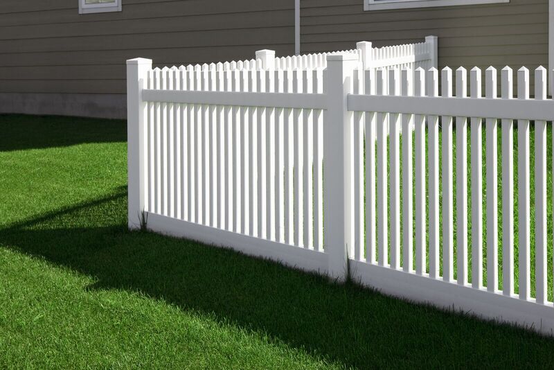 White vinyl scalloped picket fence beside a home with a stepped-up privacy run behind