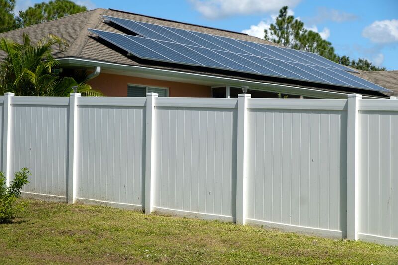 White vinyl privacy fence in six-by-six panels behind a home with rooftop solar