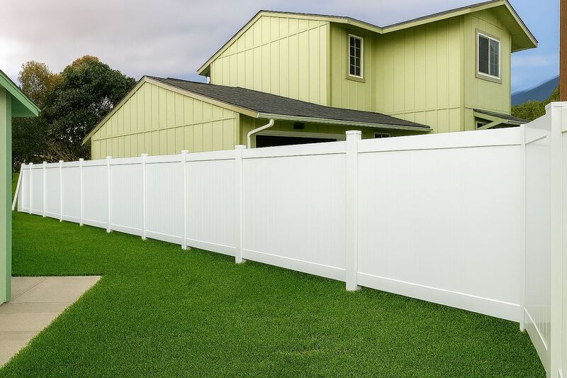 Long white vinyl privacy fence running along a side yard lawn