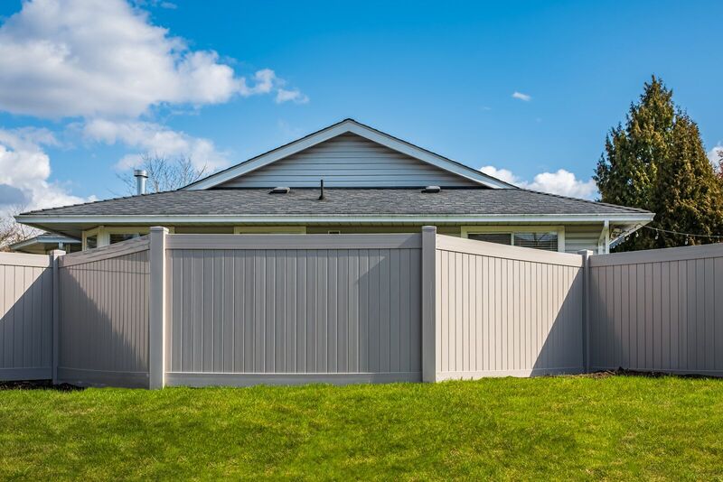 Tan vinyl privacy fence with angled corner returns around a backyard