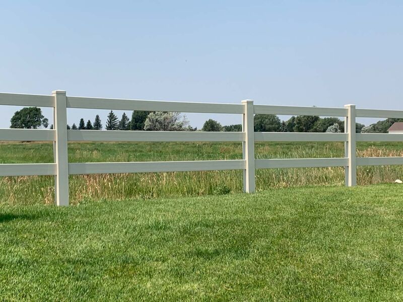 Tan vinyl three-rail ranch fence along an open pasture