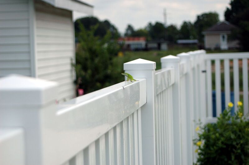 Close detail of a white vinyl fence post cap and top rail