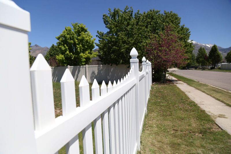 White vinyl picket fence running along a sidewalk
