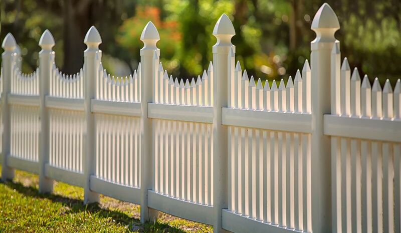 Close view of a white vinyl scalloped picket fence with gothic caps