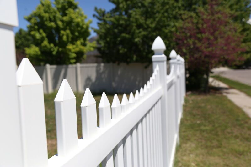 White vinyl scalloped picket fence running along a sidewalk