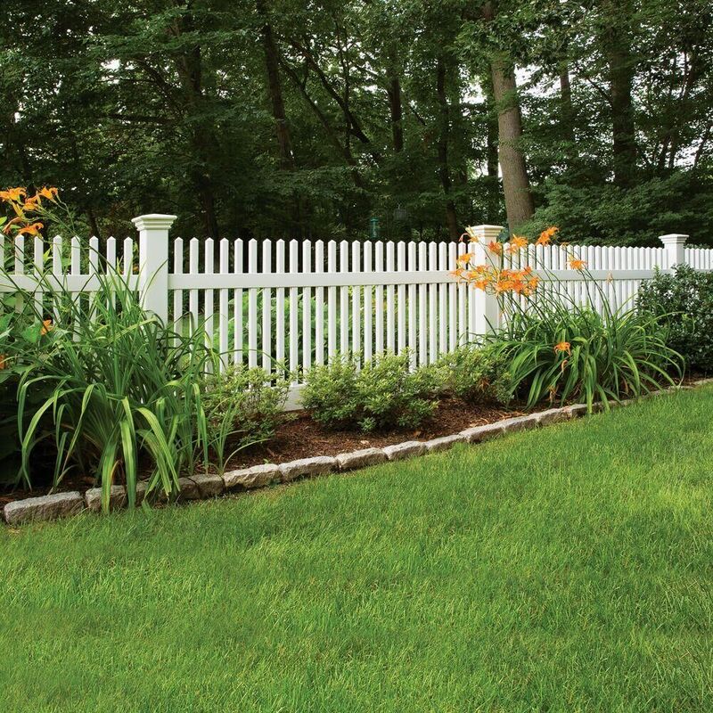 White vinyl picket fence beside a landscaped planting bed