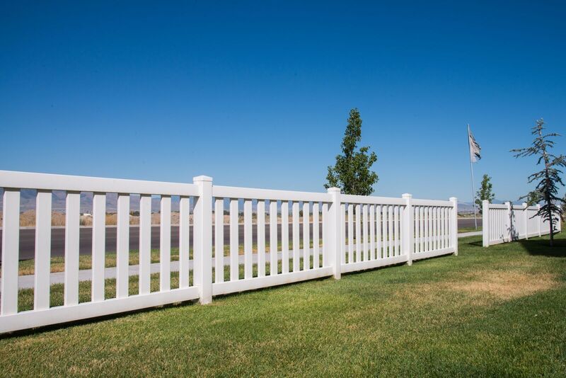White vinyl wide-spaced picket fence along an open field