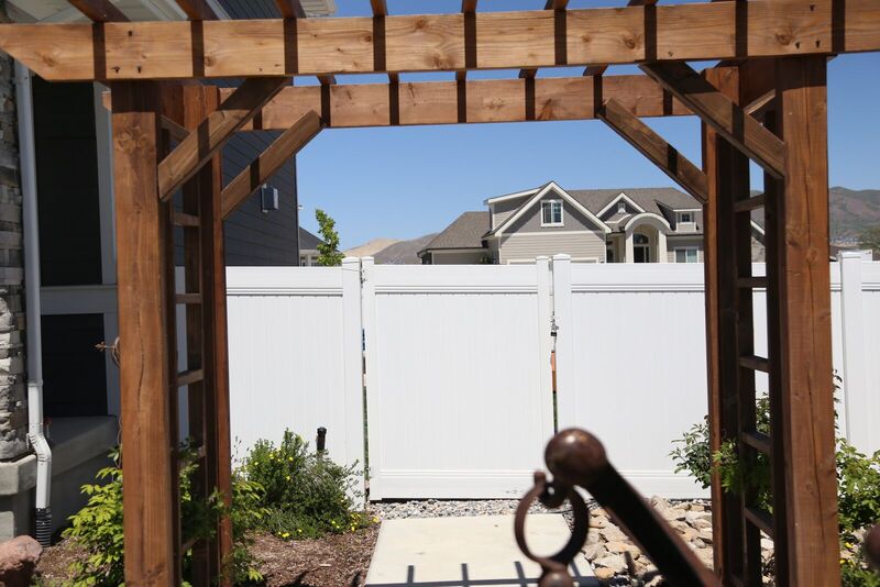 White vinyl privacy gate seen through a wood pergola