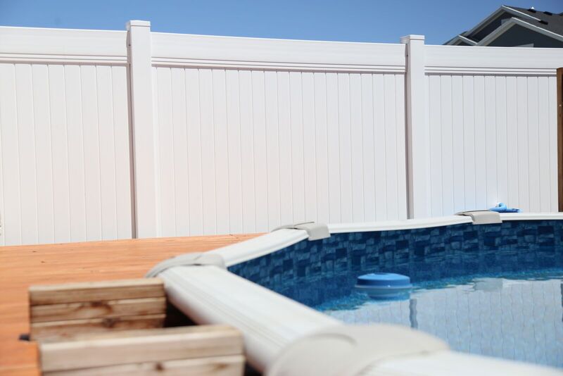 White vinyl privacy fence behind an above-ground pool