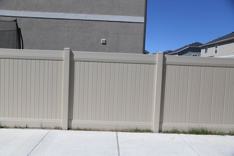 Tan vinyl privacy fence along a sidewalk
