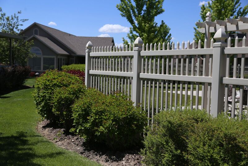 Tan semi-privacy vinyl fence in a landscaped yard with a pergola