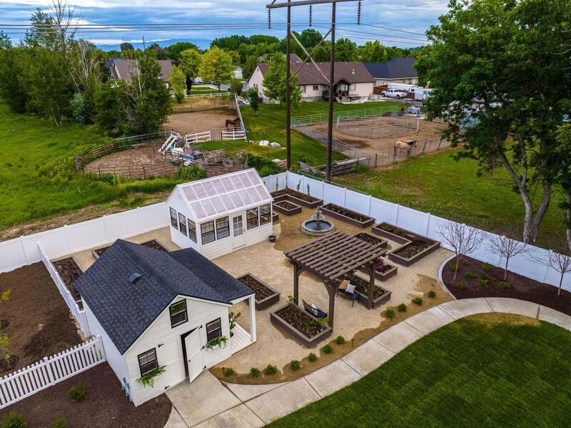 Aerial view of a white vinyl privacy fence enclosing a greenhouse and raised-bed garden