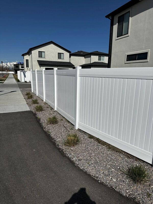 White vinyl privacy fence running along a neighborhood sidewalk
