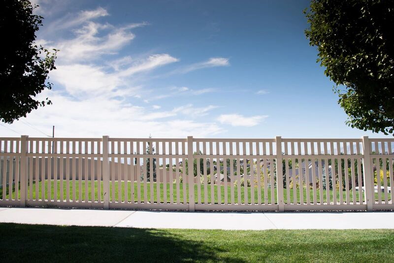 Tan vinyl semi-private fence running along a sidewalk